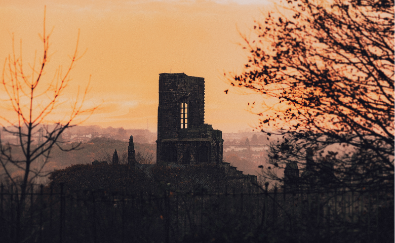 A surviving wall of an abbey on top of a hill.