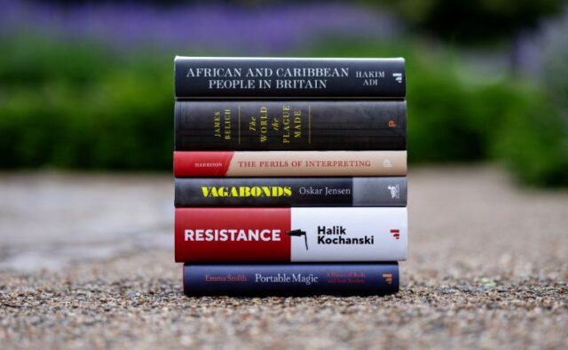 The six books shortlisted for the 2023 Wolfson History Prize on a path outside. Blurred purple and green plants are visible in the background. The books are, from top down - African and Caribbean People in Britain: A History by Hakim Adi; The World the Plague Made: The Black Death and the Rise of Europe by James Belich; The Perils of Interpreting: The Extraordinary Lives of Two Translators between Qing China and the British Empire by Henrietta Harrison; Resistance: The Underground War in Europe 1939-1945 by Halik Kochanski; Vagabonds: Life on the Streets of Nineteenth Century London by Oskar Jensen; Portable Magic: A History of Books and their Readers by Emma Smith